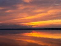 Glühende Wolken spiegeln sich am Wasser des Chiemsees